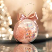 Bombka akrylowa polskiej produkcji o średnicy 12 cm, w środku zamknięte piórka w kolroze brzoskwiniowym, na górze bombki kokardka też w kolorze brzoskwiniowym. Napis i grafika wykonana z holograficznej folii samoprzylepnej, tu na zdjęciu z imieniem Kaja.